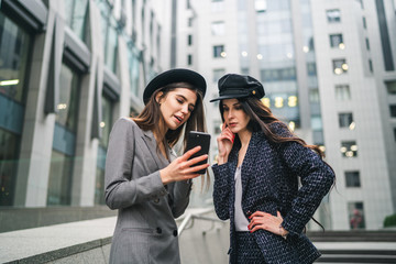 Outdoor shot of two young female friends wearing smart fashionable outfit