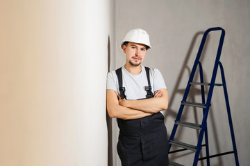 Portrait of young man worker industrial engineer in uniform and helmet standing like a boss at white background isolated. Safety equipment. Home renovation concept. Copyspace for text