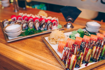 Close-up Set Philly philadelphia eel smoked philadelphia Red Green dragon California ,Ebi Roll Rainbow rolls assorti ginger seaweed in night dining restaurant. Delicious Sushi rolls served in a bar.