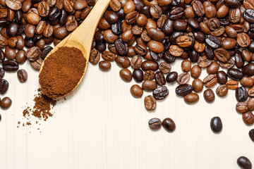 Coffee beans and ground coffee in wooden spoon