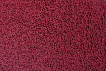 Texture of old red paint on a concrete wall a concrete wall. Chipped plaster on the wall weathered with cracks and scratches