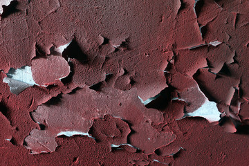 Texture of old red paint on a concrete wall a concrete wall. Chipped plaster on the wall weathered with cracks and scratches