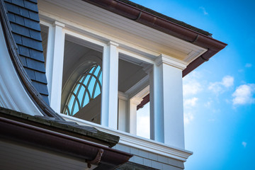 Windows, columns, rain gutters, millwork, and trim of modern home exterior.