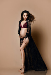 Fototapeta premium Pregnancy, maternity, preparation and expectation concept. Beautiful fashion pregnant woman holds hands on belly 
