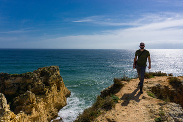 Young man walks toward camera ocean cliff Portugal