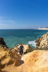 Girl hiker climbing to cliff in Algarve, Portugal