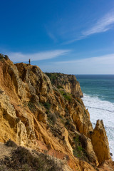 Hiker looks out over ocean horizon from on top of cliff
