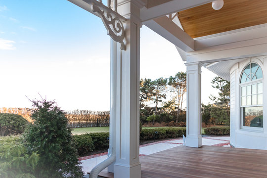 Pillars, millwork, and front window overlooking patio and deck of house with a view of blue skies