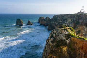 Man running to cliff ponta da Piedade Portugal with lighthouse
