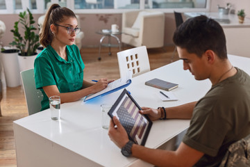 Obraz premium Female doctor having and depressed military officer during psychotherapy treatment at clinic.
