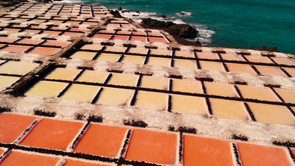 24 November 2018 La Palma Canary Islands, Salinas Marinas de Fuencaliente, Salts Flats and Mine showing multi coloured salt water fields aganst blue sky and waves