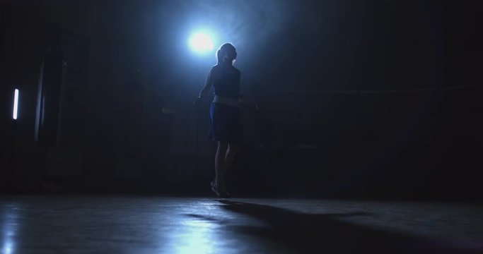 Woman boxer jumping on skipping rope in the Boxing hall with a ring