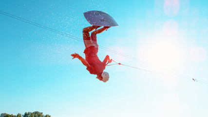 SUN FLARE: Cinematic shot of man flipping over the sun while wakeboarding.