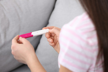 Young woman with pregnancy test indoors, closeup. Gynecology and childbirth