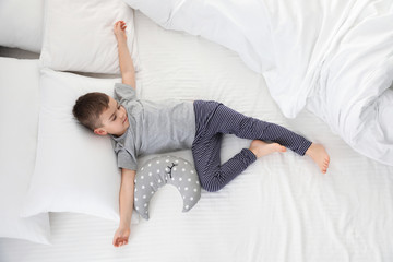 Cute little boy with toy sleeping on bed, above view