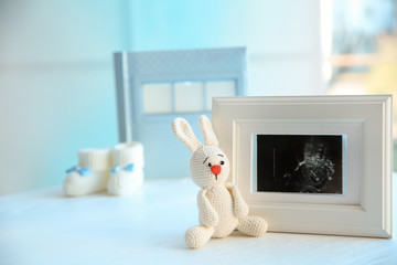 Ultrasound photo of baby and toy on table indoors, space for text