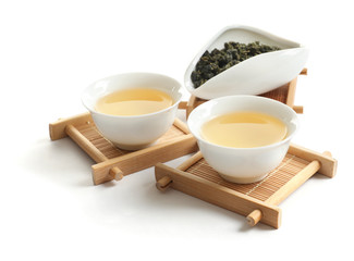 Cups of Tie Guan Yin oolong and chahe with tea leaves on white background