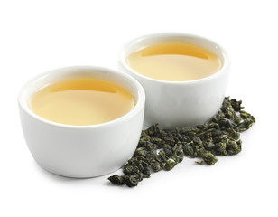 Cups of Tie Guan Yin oolong and tea leaves on white background - obrazy, fototapety, plakaty