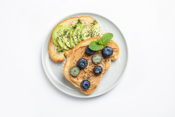 Fototapeta na wymiar Plate of tasty toasts with avocado, blueberries and chia seeds on white background, top view