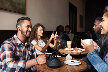 Smiling friends drinking coffee while sitting together in a cafe