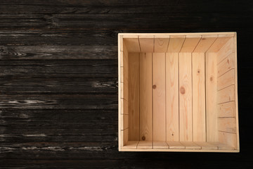 Naklejka na ściany i meble Open empty wooden crate on dark background, top view with space for text