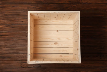 Open empty wooden crate on color background, top view