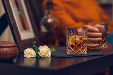 Glass of alcohol, flowers, and silhouette of woman in background, lifestyle photo