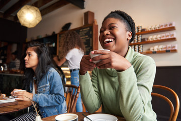 Young woman laughing over coffee with friends in a cafe