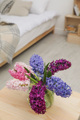 Beautiful hyacinths in glass vase on table indoors. Spring flowers
