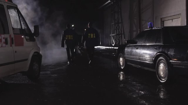 FBI agents at the crime scene, rear view. Scene. Agents of the Federal Bureau of Investigation walking in slow motion