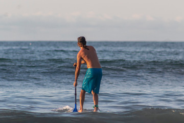 Hombre haciendo paddle board durante vacaciones en la playa de Sayulita.