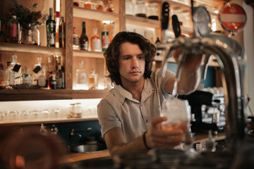 Bartender preparing drinks behind a bar counter at night