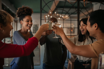Friends cheering with drinks together in a bar at night