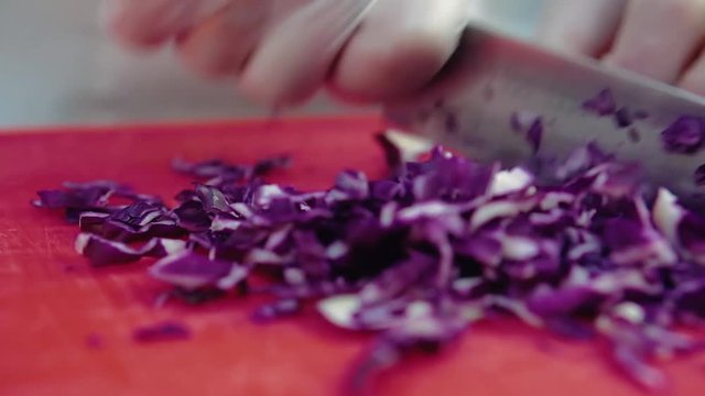 cook cuts a blue onion with a knife. Close up.