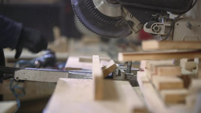 Close up of a young man in a furniture factory cutting the wooden pieces for the sofa