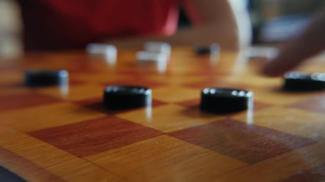Old people playing checkers in strange game on chessboard at home. Close up
