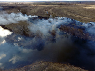 The smoke from the burning of dry grass (drone image).Local residents set fire to the grass specifically. Small animals are bending. Local features and habits. Near Kiev,Ukraine