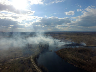 The smoke from the burning of dry grass (drone image).Local residents set fire to the grass specifically. Small animals are bending. Local features and habits. Near Kiev,Ukraine