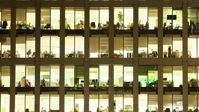 Timelapse of the exterior of an office block at night revealing the daily activity of office workers night themes of routines working late deadlines