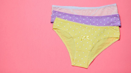 Neatly stacked stack of women's panties on a pink background. Fashionable concept. Beautiful lingerie.