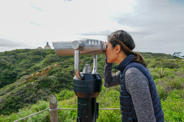 Asian sporty woman looking inside binocular telescope on the tip of the Point Loma Peninsula in San...