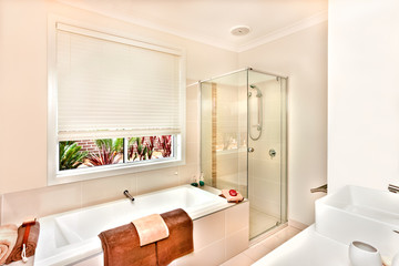 Modern bathroom with bath tub and bathing area prepared with towels
