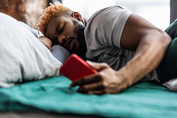 Obraz premium Pleasant nice man looking at his smartphone screen
