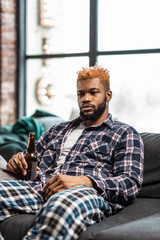 Sad gloomy man drinking beer at home