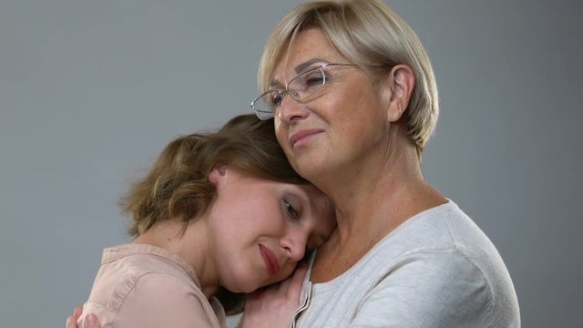 Mother hugging adult daughter isolated on background, parental love and support