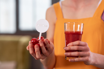 Skinny girl in bright top holding tomatoes and glass of juice