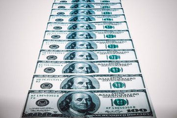 Banknotes of dollars are stacked in a row. Vignetting white background.