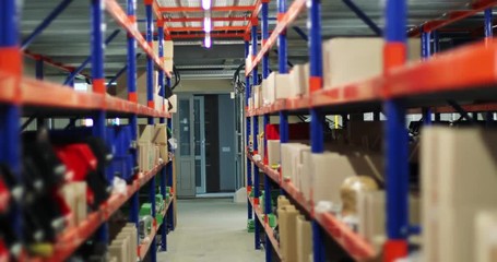 View of the interior inside industrial warehouse. Variety of spare parts boxes on shelves and tires on the floor.
