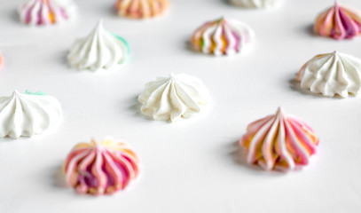 Multi-colored meringue on a white background. Sweets on the photo. Pattern with meringue on a white background. Sweet holidays