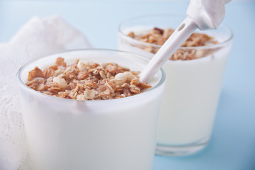 Granola with yogurt in glass on a blue table.